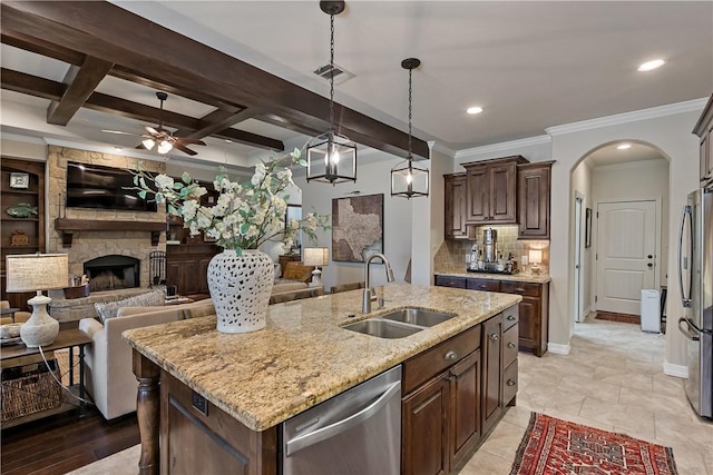 kitchen featuring arched walkways, a sink, visible vents, open floor plan, and appliances with stainless steel finishes