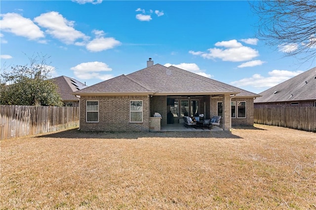 rear view of house with a patio area, brick siding, a yard, and a fenced backyard