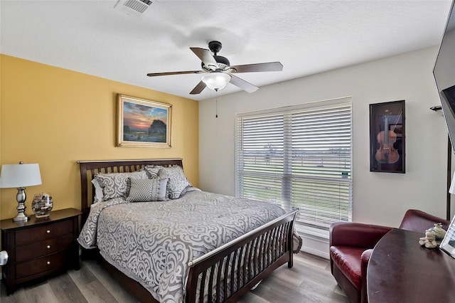 bedroom with hardwood / wood-style floors, a textured ceiling, and ceiling fan