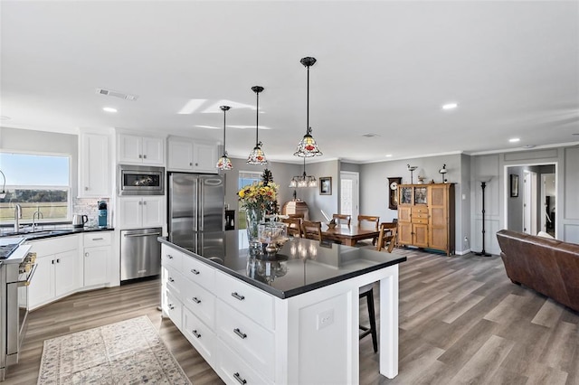 kitchen featuring stainless steel appliances, pendant lighting, white cabinets, hardwood / wood-style floors, and a center island