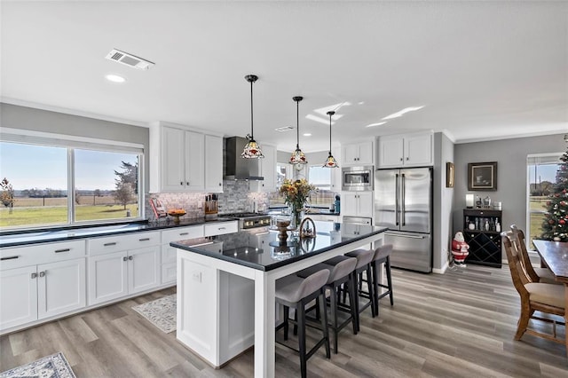 kitchen with appliances with stainless steel finishes, a breakfast bar, pendant lighting, a center island, and white cabinetry