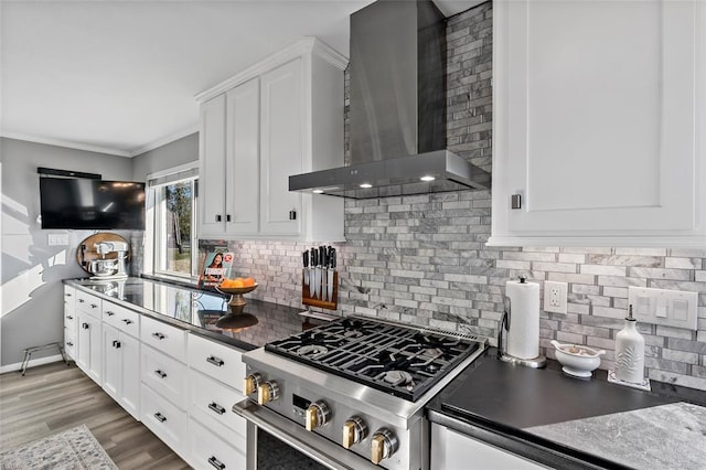 kitchen with stainless steel stove, white cabinetry, and wall chimney range hood