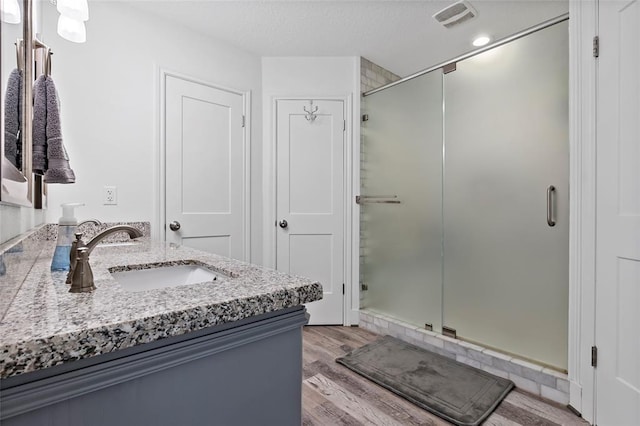 bathroom featuring vanity, hardwood / wood-style flooring, and a shower with door