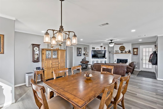 dining area featuring hardwood / wood-style floors, ceiling fan with notable chandelier, and ornamental molding