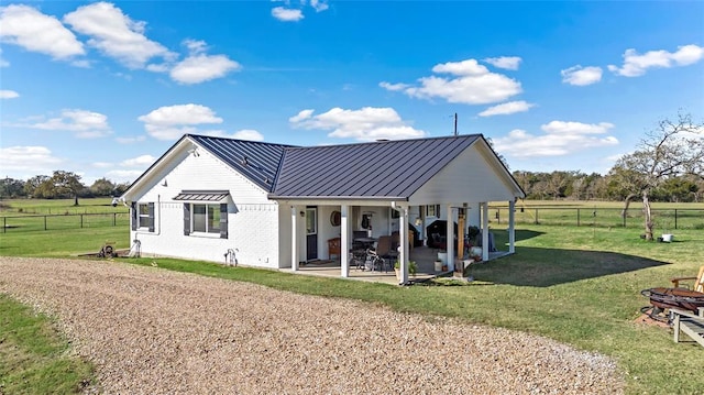 back of house featuring a patio area, a yard, and a rural view