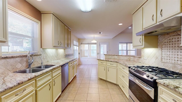 kitchen featuring sink, hanging light fixtures, light tile patterned floors, appliances with stainless steel finishes, and cream cabinetry