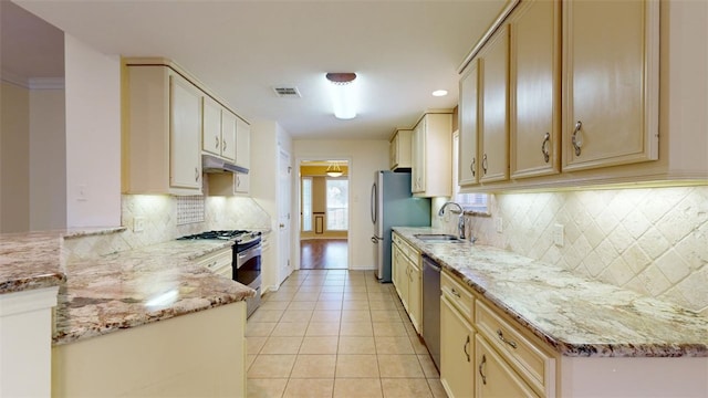 kitchen featuring stainless steel appliances, light stone countertops, sink, and light tile patterned floors