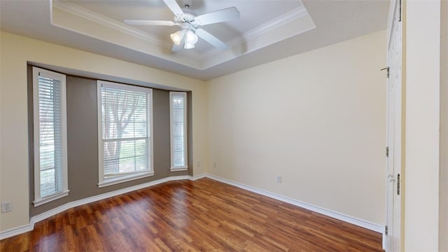 unfurnished room featuring ornamental molding, dark hardwood / wood-style floors, ceiling fan, and a tray ceiling