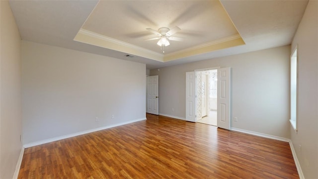 spare room featuring crown molding, ceiling fan, wood-type flooring, and a tray ceiling