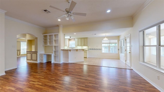 unfurnished living room with ornamental molding, a wealth of natural light, and light hardwood / wood-style floors