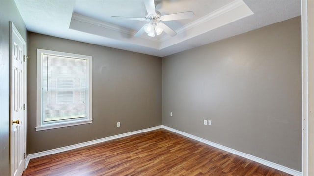 spare room with a raised ceiling, ceiling fan, ornamental molding, and dark hardwood / wood-style flooring