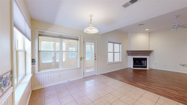 unfurnished living room with a wealth of natural light, ceiling fan, and light tile patterned floors