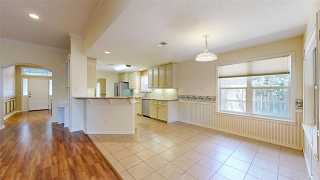 kitchen with light tile patterned floors, crown molding, appliances with stainless steel finishes, decorative light fixtures, and kitchen peninsula