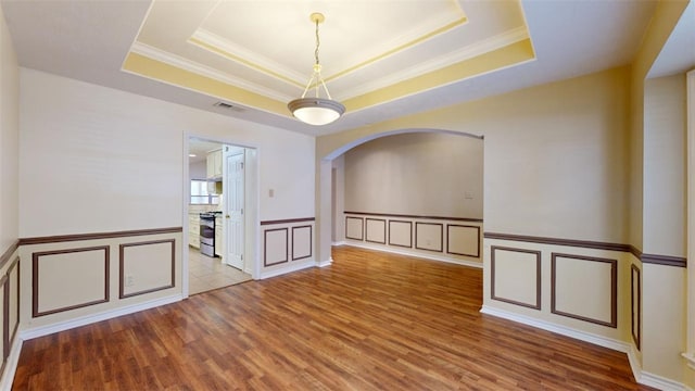 spare room with hardwood / wood-style flooring, crown molding, and a raised ceiling