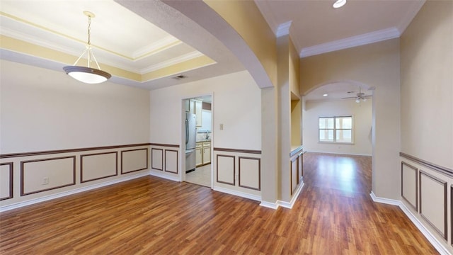 spare room featuring crown molding, a tray ceiling, wood-type flooring, and ceiling fan