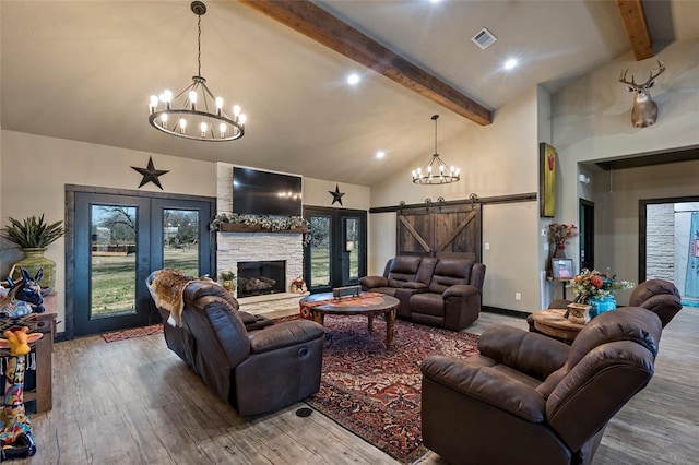 living room featuring a notable chandelier, beamed ceiling, visible vents, and wood finished floors