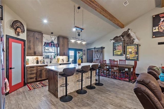 kitchen featuring visible vents, light countertops, a kitchen bar, a barn door, and light wood-type flooring