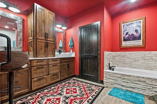 bathroom with vanity, a bath, and wood finished floors