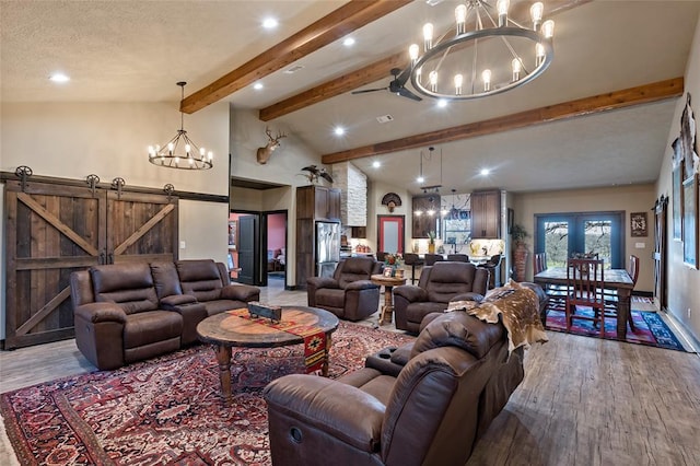 living room with a barn door, wood finished floors, beamed ceiling, and a chandelier