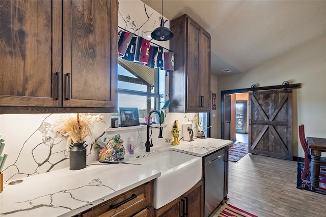 kitchen featuring a sink, light countertops, dark brown cabinets, stainless steel dishwasher, and a barn door