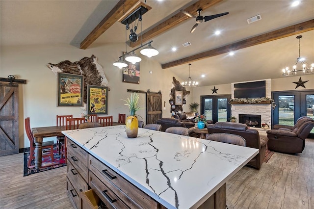 kitchen featuring a barn door, light wood-style floors, visible vents, and ceiling fan with notable chandelier