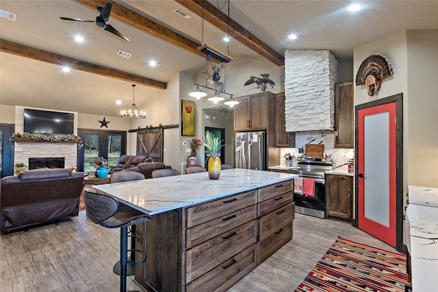 kitchen featuring ceiling fan, stainless steel appliances, light wood-style floors, and a breakfast bar area