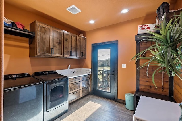 washroom featuring light wood-type flooring, visible vents, washing machine and dryer, recessed lighting, and cabinet space