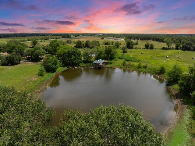 aerial view at dusk featuring a rural view and a water view