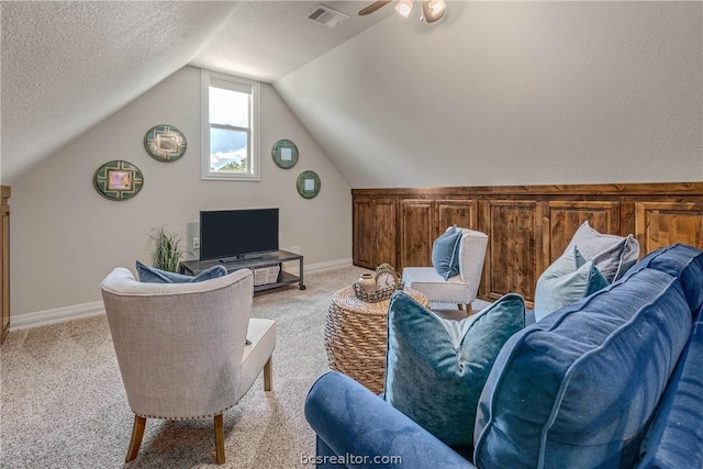 living room with a textured ceiling, light carpet, and vaulted ceiling