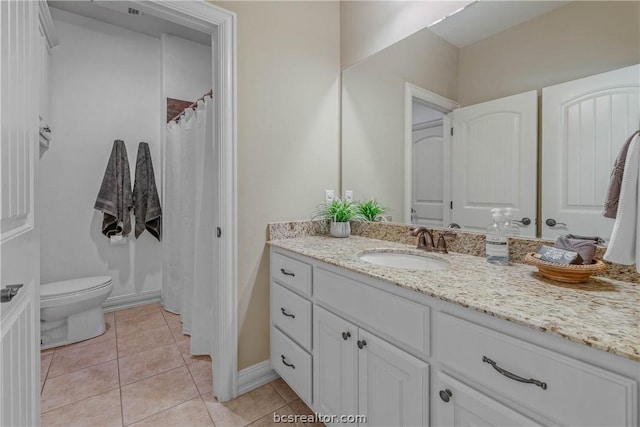 bathroom with toilet, vanity, and tile patterned floors