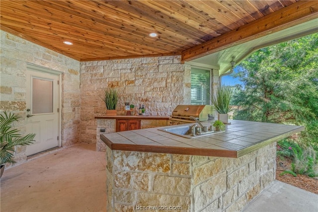 exterior space featuring tile countertops, wood ceiling, a healthy amount of sunlight, and sink