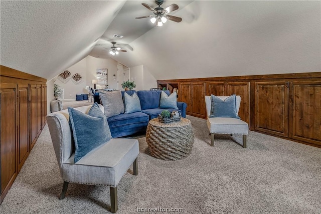 carpeted living room with a textured ceiling, vaulted ceiling, and ceiling fan