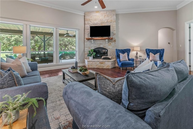 living room with a fireplace, wood-type flooring, ceiling fan, and crown molding