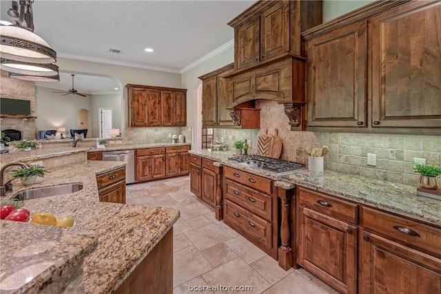 kitchen featuring stainless steel appliances, crown molding, sink, a fireplace, and hanging light fixtures