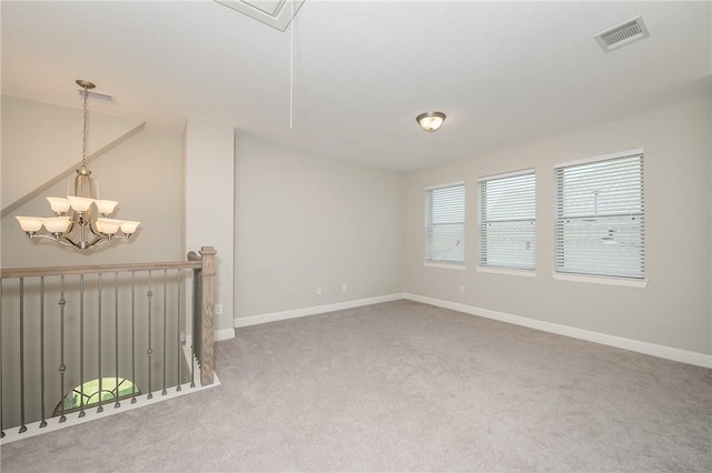 carpeted spare room featuring an inviting chandelier