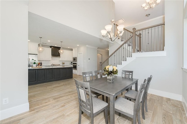 dining space featuring crown molding, light wood-type flooring, and a notable chandelier