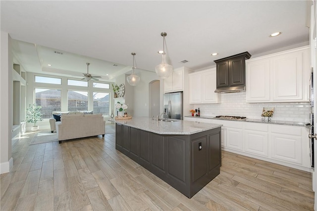 kitchen featuring stainless steel appliances, light hardwood / wood-style flooring, white cabinets, and hanging light fixtures