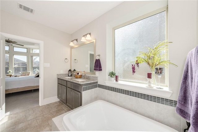 bathroom with ceiling fan, vanity, and tiled bath