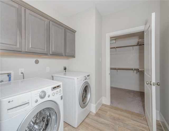 laundry room featuring cabinets, light hardwood / wood-style floors, and washer and clothes dryer