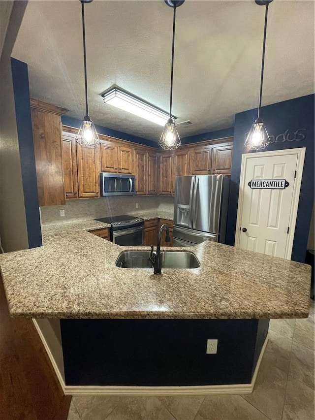 kitchen with appliances with stainless steel finishes, sink, pendant lighting, and kitchen peninsula