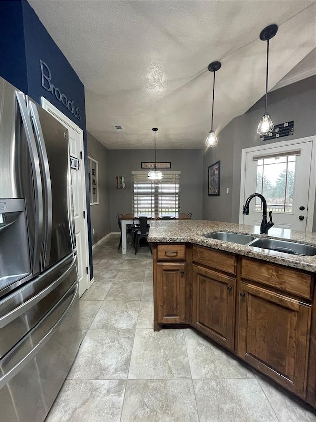 kitchen featuring sink, hanging light fixtures, stainless steel fridge, and plenty of natural light