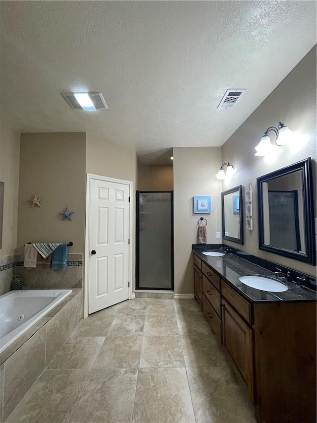 bathroom featuring a textured ceiling, separate shower and tub, and vanity