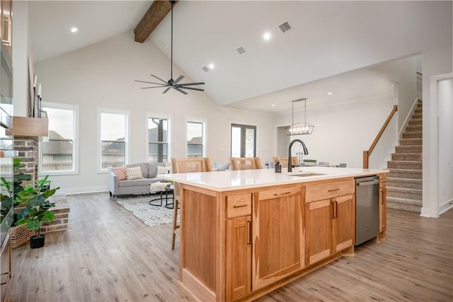 kitchen with pendant lighting, stainless steel dishwasher, an island with sink, and a wealth of natural light