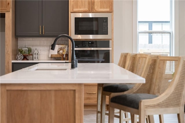 kitchen with built in microwave, tasteful backsplash, sink, and oven