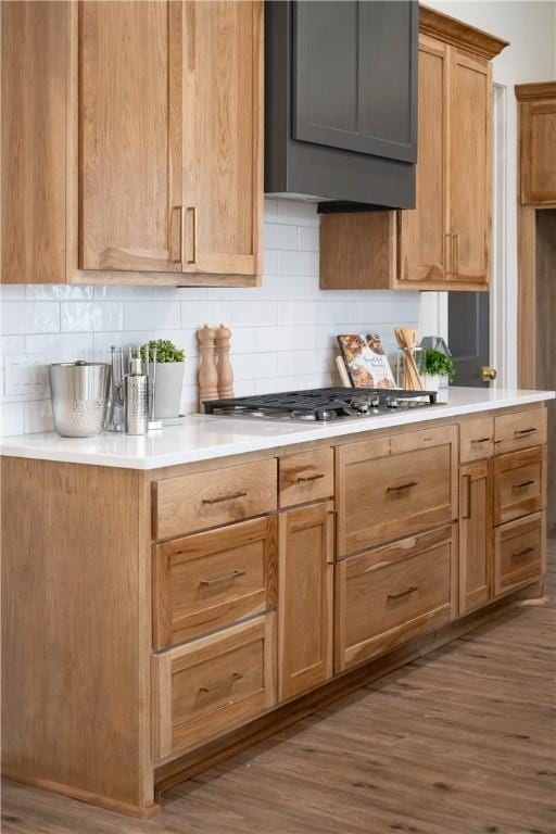 kitchen featuring backsplash, hardwood / wood-style flooring, and stainless steel gas cooktop