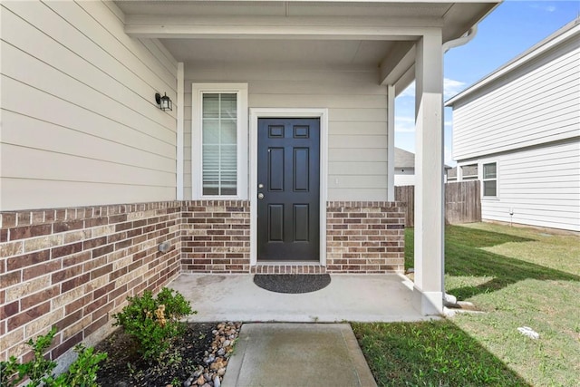 doorway to property featuring a lawn and brick siding