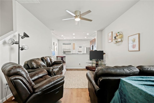 living area with light wood finished floors, ceiling fan, and baseboards