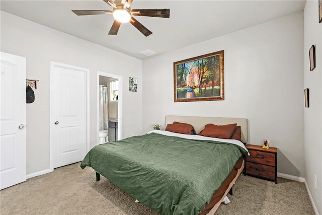 bedroom featuring baseboards, ensuite bath, and light carpet