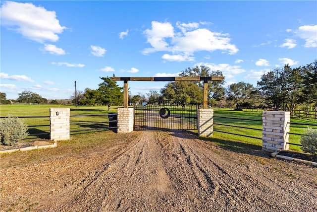 view of gate featuring a yard, a rural view, and fence