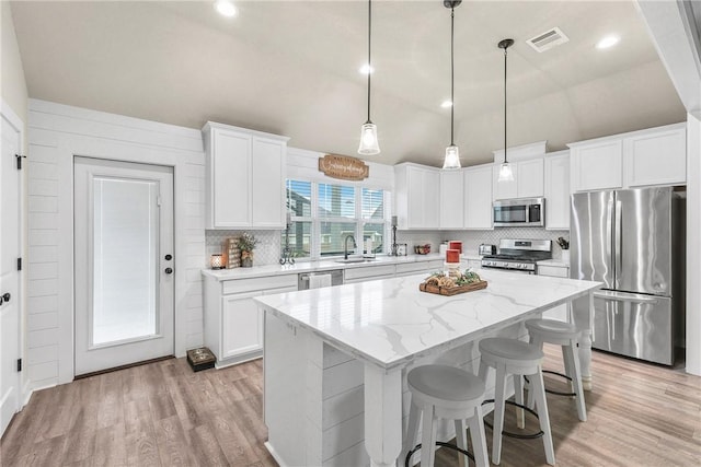 4019 Heru Ct, College Station, TX 77845 - kitchen featuring stainless steel appliances, light wood-style flooring, a center island, backsplash, and vaulted ceiling